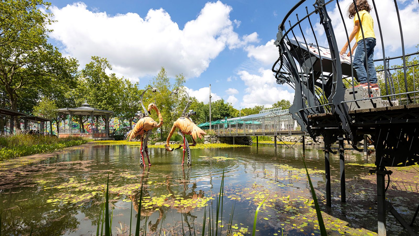 Child playing with the mechanical pink flamingos of the Animals of Place Napoléon in La Roche-sur-Yon