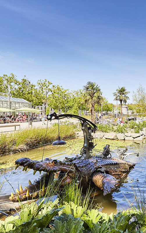 Family playing with the mechanical crocodile of the Place Napoléon Animals in La Roche-sur-Yon